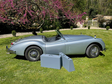 Jaguar XK140 Roadster with bespoke handcrafted leather luggage set displayed beside the car, custom-made in France by Laurent Nay Maroquinerie to fit the original trunk perfectly.