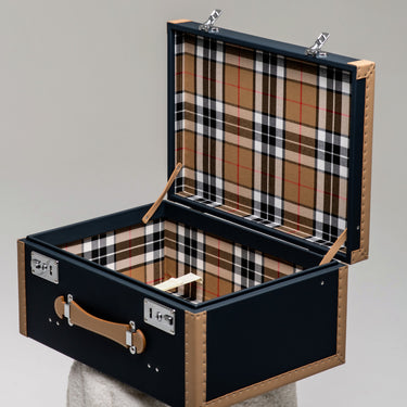 Open Heritage decorative trunk with a black exterior, natural leather trim and tartan lining, handcrafted in France.