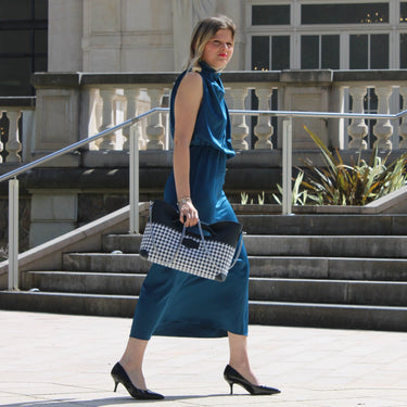 Woman carrying the Laurent Nay Léa handbag in black leather and black-and-white houndstooth fabric, handcrafted in France.